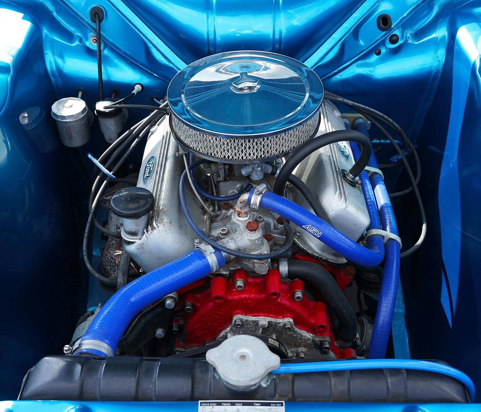 Detailed view of a classic car engine showcasing chrome parts and vibrant blue accents.